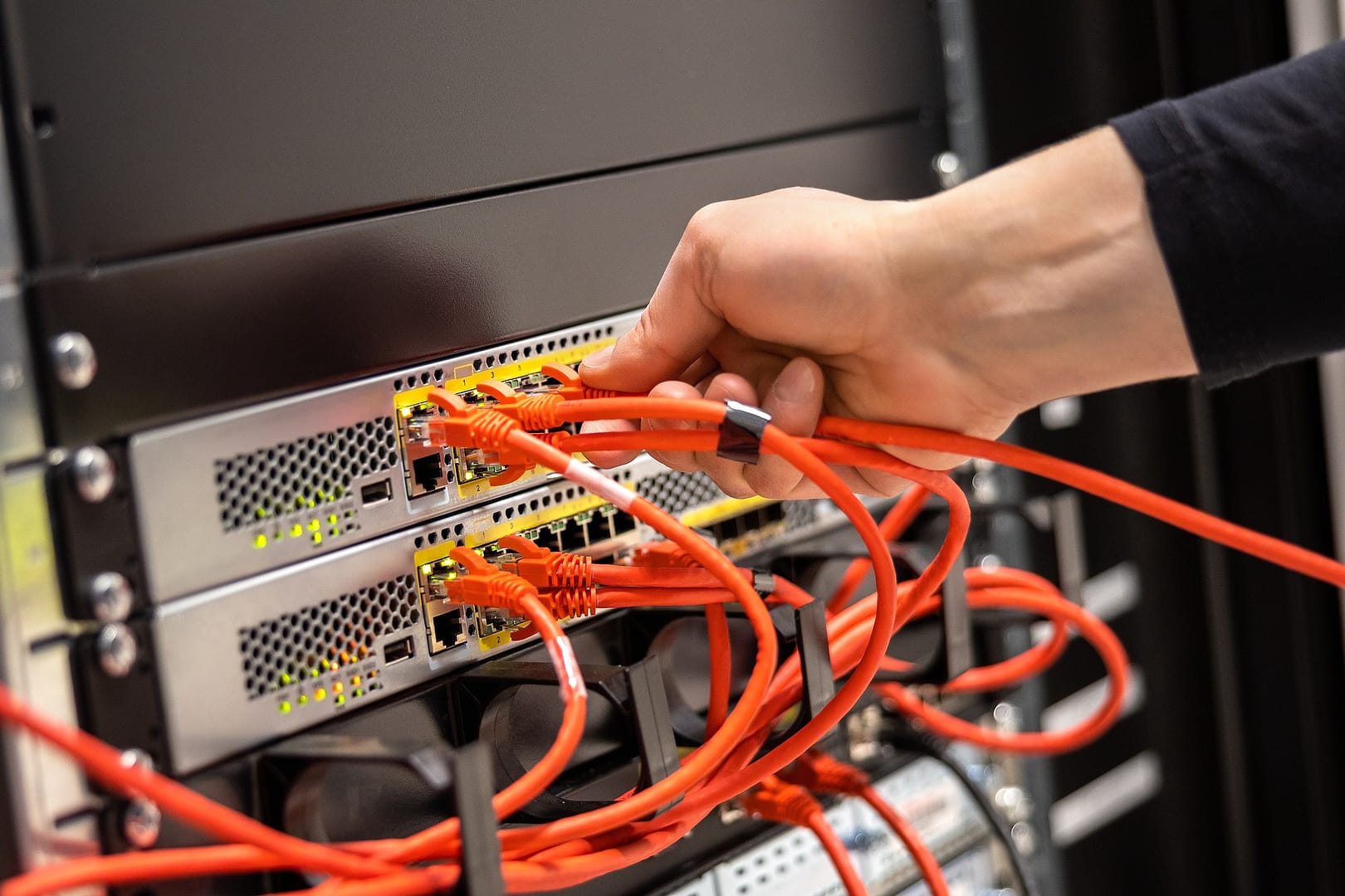 Close-up of Male Technician Plugging Network Cable In Network Router